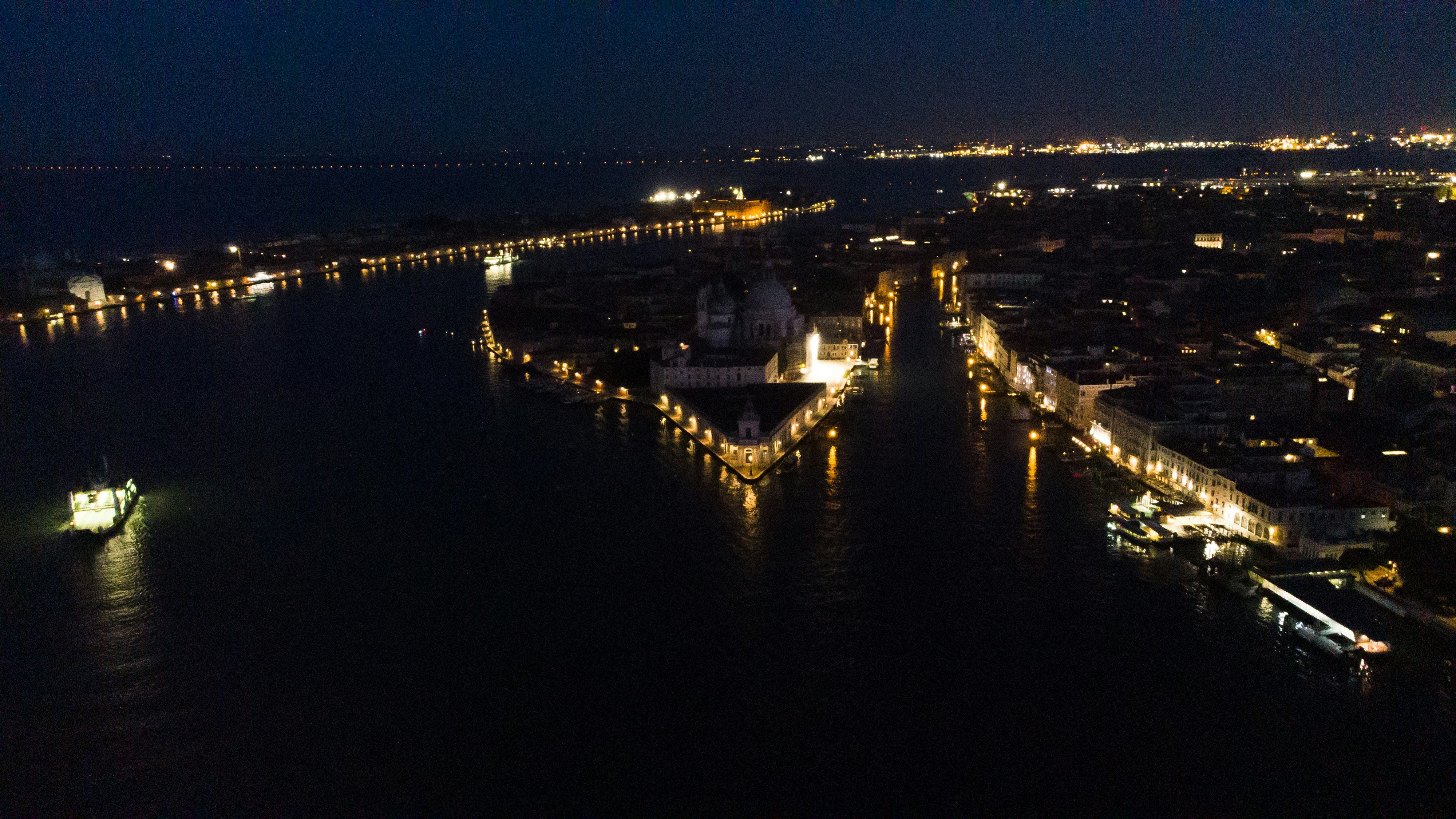 Venice and its lagoon glowing at night, seen from above.